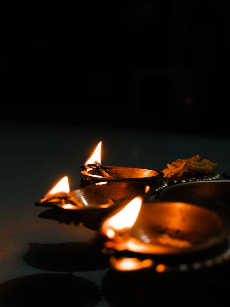 Brass three-wick diya on marigold block-print napkin